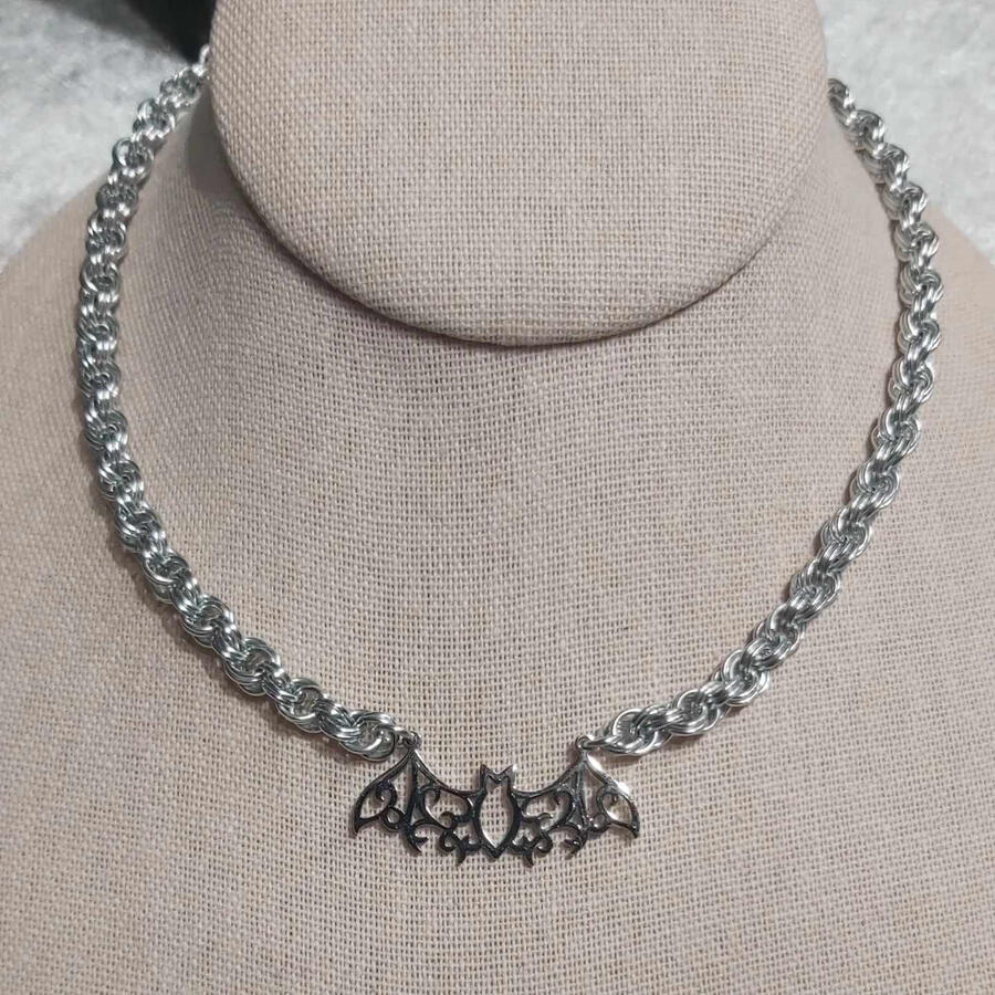 Double Spiral with Bat. Made with anodized aluminum rings and a stainless steel pendant.